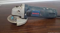 Full side view of BOSCH angle grinder showing motor housing, power switch, and grinding disc attached