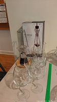 Overall view of four stemmed wine glasses, aerator decanter system with stand and wooden base, and product box.