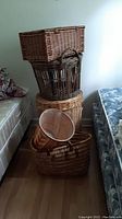 Stack of four wicker baskets including rectangular with lid on top and round hamper below.