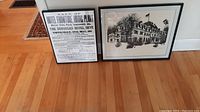 Two black framed black-and-white prints side by side on hardwood floor
