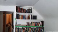 Wide view of multiple shelves filled with assorted vintage books indicating variety and worn condition