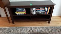 Front view of dark brown wooden cabinet with two shelves containing books and CDs.