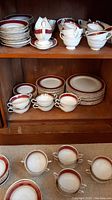 Shelves displaying stacks of matching plates, bowls, cups, saucers, and a gravy boat