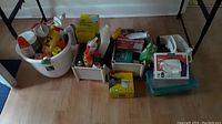Wide shot of bucket with cleaning products and two storage bins containing cleaning wipes, baking soda, kitchen bags, and compostable bags.