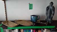 Wide shelf shot displaying all five items: stone figurine, ceramic mug, brass candle snuffer, shell dish, and oval tray