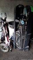 Full view of golf bag, hard travel case, and golf caddy pull cart in garage setting