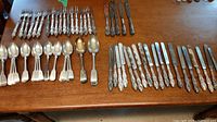 Overhead view of all flatware laid on wooden table showing spoons, forks and knives