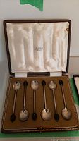 Set of six silver teaspoons displayed in fitted brown box with cream satin interior lid, lid stamped A&J Smith Aberdeen.