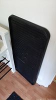 Black boot tray leaning against wall near shoe bench