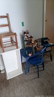 Wide shot of all items: blue kids table, four kids chairs, doll bed rocker, two dolls on chairs, Holly Hobby play oven on table