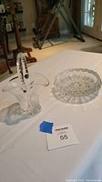 Crystal basket and dish on a white tablecloth with background furniture, showing overall lot contents