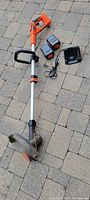 Full view of Black & Decker cordless edger with two lithium batteries and battery charger laid out on pavers.