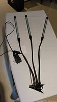 Overview of LED grow light with three adjustable wands, power cord, and mounting clip, laid flat on white surface