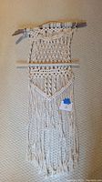 Full view of the macrame wall hanging showing the cotton yarn design and driftwood base.