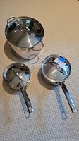 All three stainless steel pots together showing size differences and handles