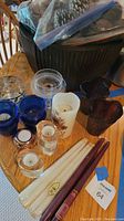 Photo showing the variety of candles and votive holders including white and cranberry taper candles, dried flower candle, and blue, clear, and brown glass votive holders