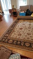 Area rug covering floor between couch and flooring, showing floral pattern and decorative border.