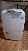 Front view of white Garrison dehumidifier with instruction manual on top.