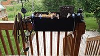 Overall view of the flower rail pot on wooden deck railing with cat ornament and wind chimes hanging nearby.