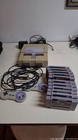 SNES console, two controllers, cables and stack of cartridges