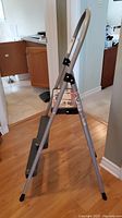 Side view of the 3ft folding step ladder showing metallic frame, three steps with black plastic treads, and curved handle.