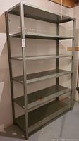 Full view of the five-tier metal workshop shelving unit showing overall structure and paint finish in a basement setting.