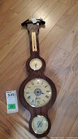 Full view of the vintage wooden weather station with clock, barometer, and hygrometer on a wood floor.