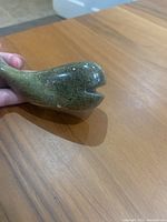 Close-up of the whale statue head showing the mouth detail and smooth polished green stone surface.
