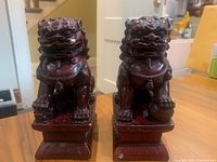 Front view of pair of reddish-brown Fu Foo Dog statues on rectangular bases