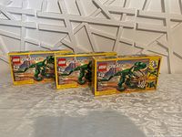 Three identical boxed LEGO Creator Mighty Dinosaur sets lined up.