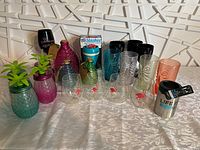 Front and angled view of assorted plastic and acrylic drinkware including pineapple shaped, tiki glasses, flamingo glasses, colored tumblers, and insulated stainless steel tumbler.