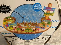 Photo of boxed floating tiki beverage bar with colorful tropical drink graphics and pool party branding.