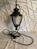 Gazebo hanging light in upright position with visible long electric cord, showing the metal and hammered glass detail.