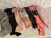 Seven girls sweaters in different colors and styles laid out for display.