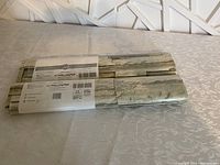 Two rolls of NU Wallpaper brand peel and stick wallpaper laid out showing stone brick pattern and packaging labels.