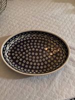 Oval ceramic serving dish handmade in Poland, showcasing Boleslawiec pottery design with circular dots and concentric rings in navy blue and cream.