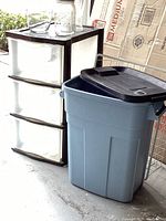 Three-drawer storage shelf, Rubbermaid trash can, and part of wire basket visible, mason jars on top of shelf