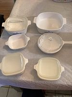 Overview of 6 Corning Ware dishes laid out on table, showing blue cornflower pattern and lids.