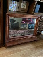 Front view of the rectangular wooden framed mirror with five key hooks below the reflective surface.