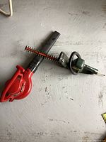 Photo showing the Black & Decker electric hedge trimmer and the Toro blower lying on the floor with visible details of handles and blades/nozzles