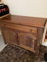 Solid wood dresser shown from an angle, emphasizing scratches and wear on top and front surfaces