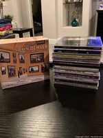 Photo of John Denver Collection box set and stack of 11 other CDs on a table.