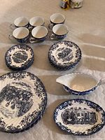 Full set arranged showing cups, saucers, plates, gravy boat and serving dish with detailed blue Coaching Scenes pattern.
