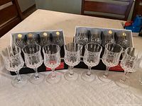 Fifteen Longchamp crystal goblets displayed. Seven goblets are unboxed, and eight goblets remain in original boxes behind them.