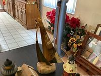 Brass sailboat on marble base displayed among other nautical decor items including lighthouses and tiny ships