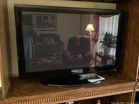 Front view of Samsung 42-inch plasma TV on black curved stand showing reflective screen and black bezel, with remote control placed on the stand