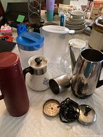 All items shown on table including percolator, pitchers, and thermos