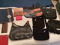 Full lot display with six purses, five wallets, folder, flashlight, and umbrella laid out on floor.