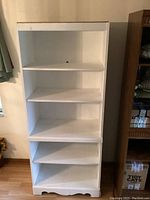 Full front view of white 5 shelf wooden bookcase showing five shelves and overall structure.