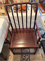 Front view of Chinese rosewood arm chair showing high spindle back and seat platform